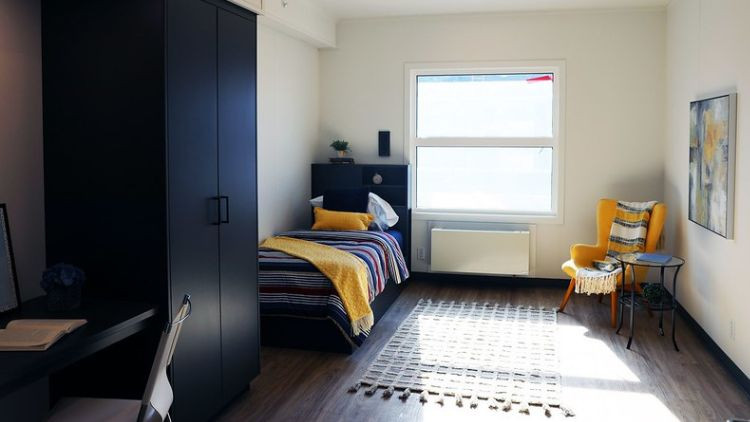Picture of a room at Red Deer Recovery Commmunity. The bedroom contains a wardrobe, an office desk, a bed and a chair.