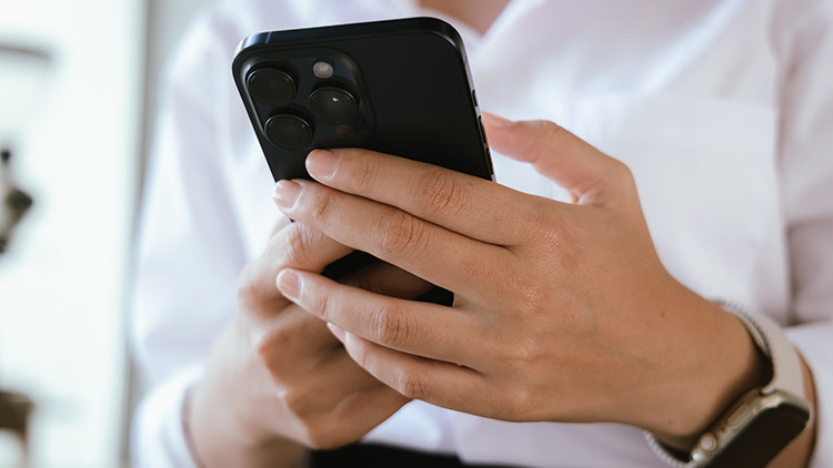 Close-up of woman's hand holding smartphone while sitting in cafe