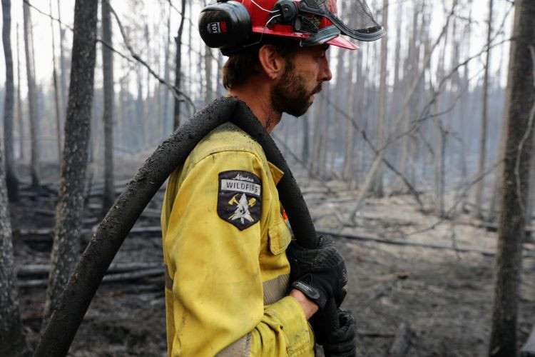 Firefighter with hose over his shoulder observes a hotspot