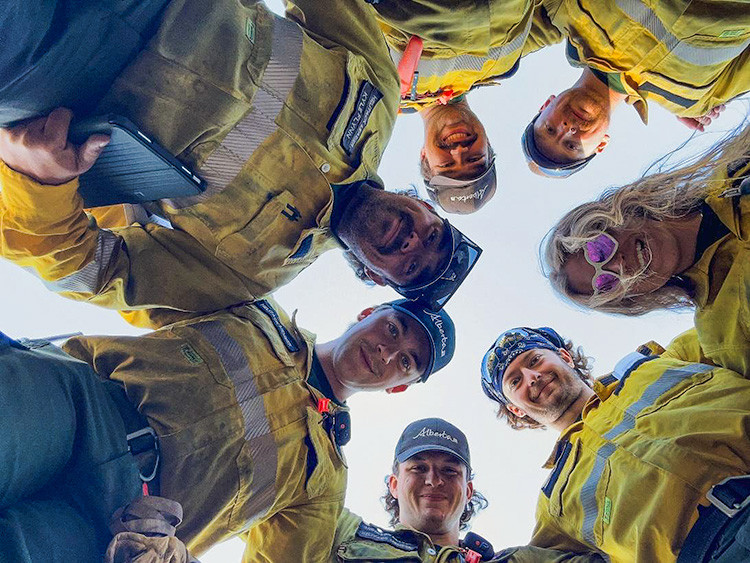 Firefighters in yellow nomex shirts smile down at the camera