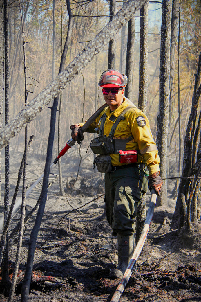 wildland firefighter putting out hotspots with hose in the black 